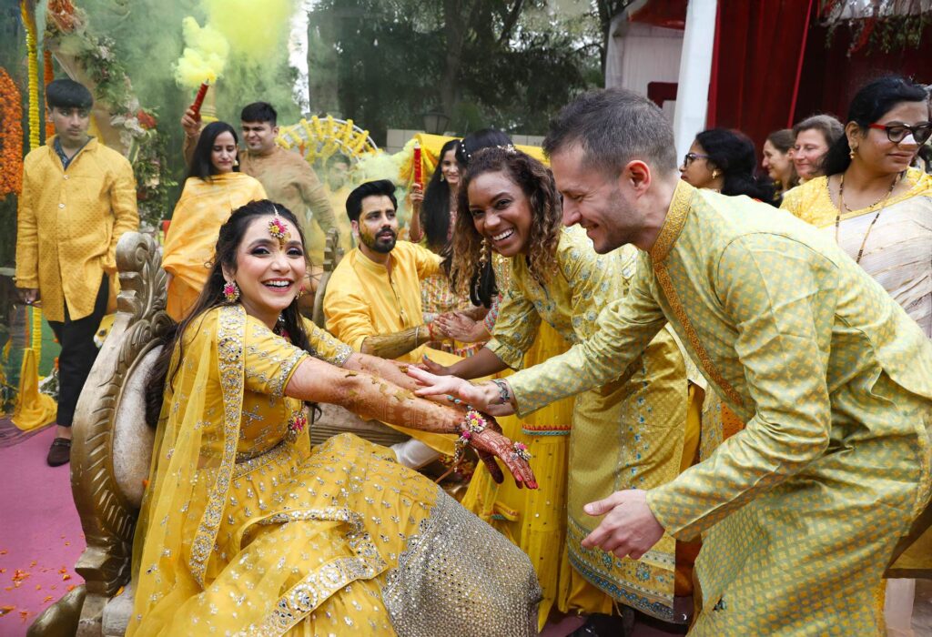 Candid moment of friends covering the bride in haldi at Indian wedding