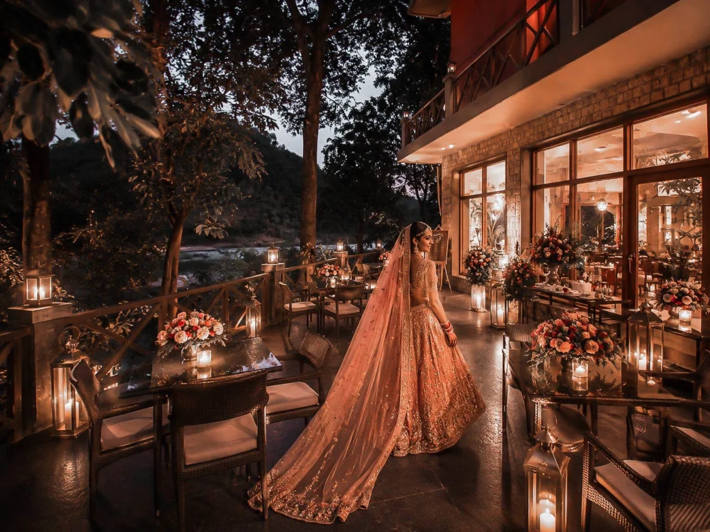 Bride walking through a lantern lit terrace reception area at Taj Corbett during twilight