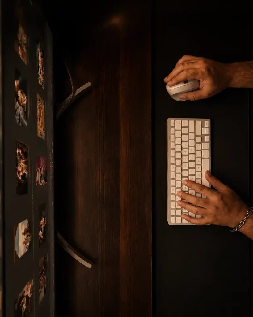 Top-down view of a professional wedding photographer reviewing and editing a wedding gallery during post-production using a desktop editing workstation.